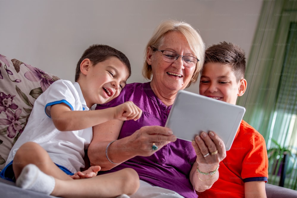 Grandmother and grandsons are making a call via internet with tablet pc to talk online to grandfather.