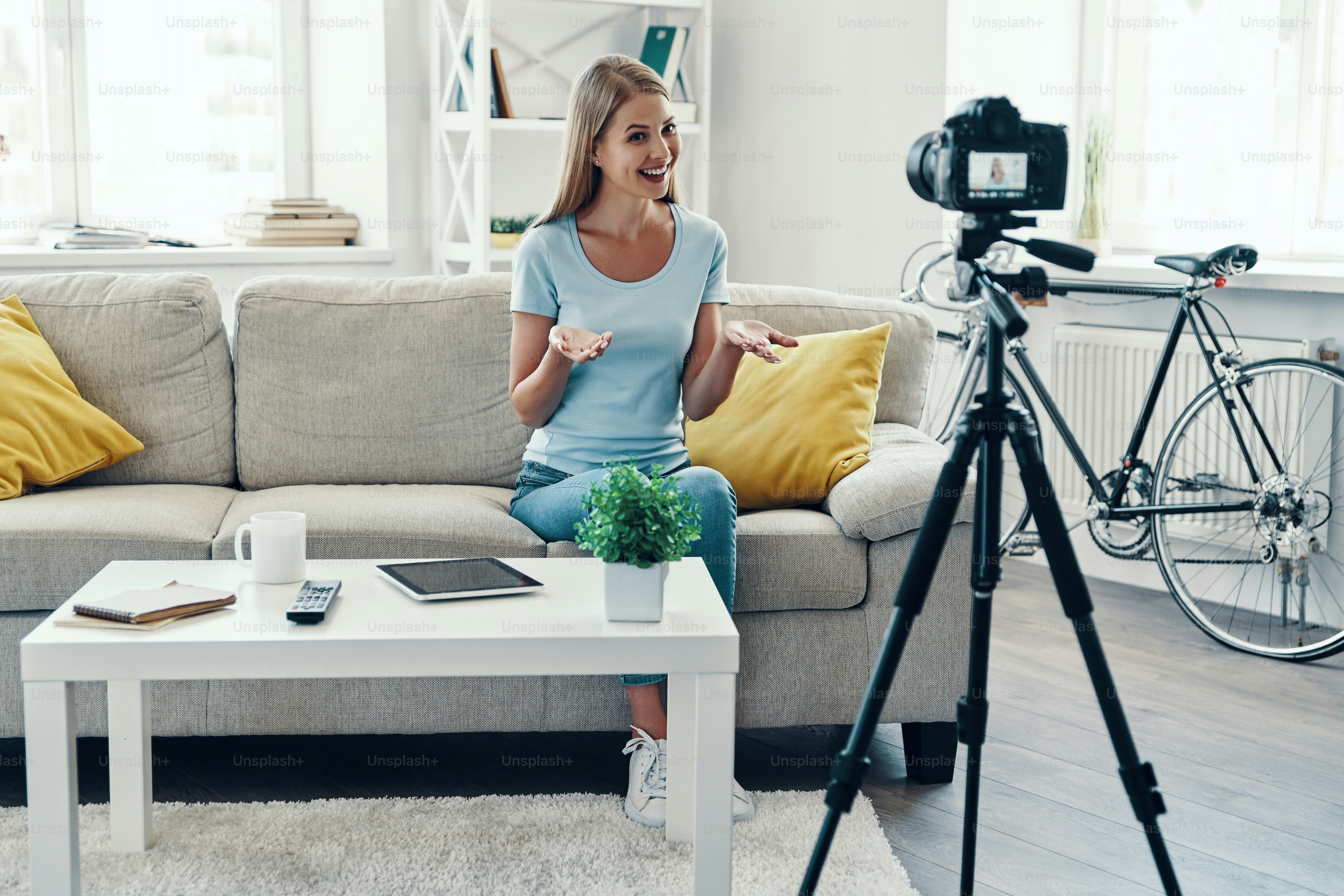Beautiful young woman smiling and gesturing while making social media video at home