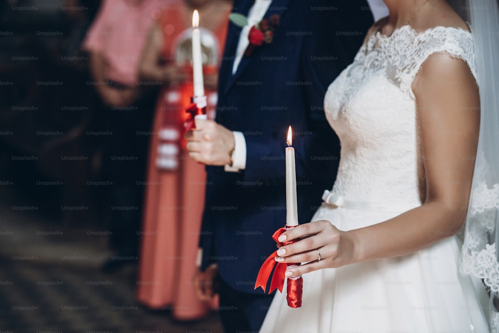 bride and groom holding candles in hands,  couple in church during wedding ceremony, religion traditions