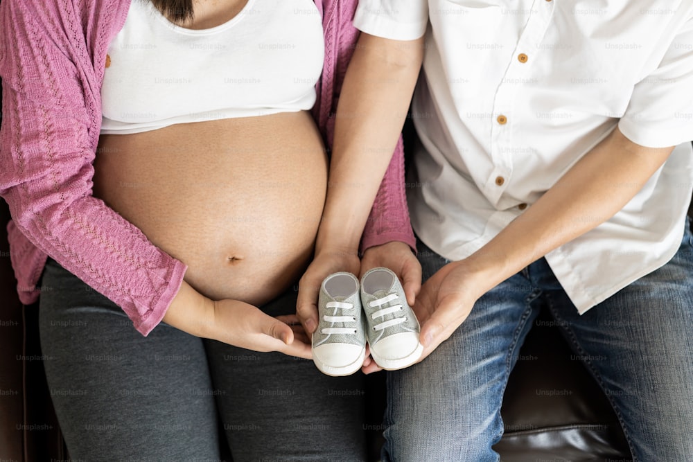 남편과 아내의 임신 한 부부는 집에서 사랑을 느끼고 휴식을 취합니다. 젊은 기대하는 여자는 임신한 배에 아기를 안고 있다. 아버지는 임산부를 돌 봅니다. 출산 및 임신 관리의 개념.