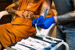 Close up of man opening steril equipment for piercing. Piercings getting ready for Procedure. Body piercing salon. Woman getting a piercing