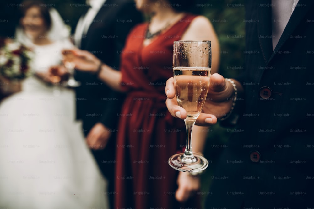 Copas de champán en la recepción de la boda, brindis de los novios. hermosa pareja de novios recién casados animando divirtiéndose y bebiendo