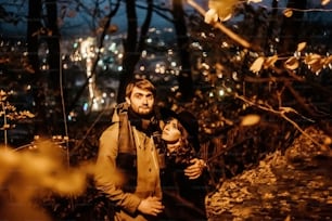 happy stylish couple hugging and holding hands with tender under yellow lantern  in night lights of the city