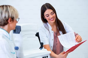 female ophthalmologist showing patient's data to a clipboard, working in an optical store. Healthcare and medicine concept.