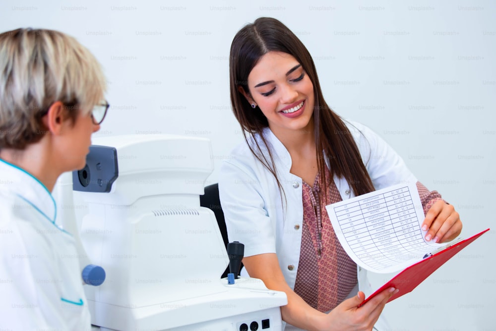 female ophthalmologist showing patient's data to a clipboard, working in an optical store. Healthcare and medicine concept.