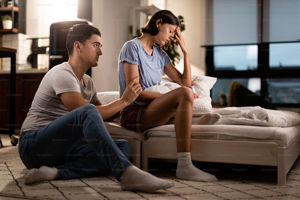 Jeune femme mécontente ignorant son petit ami qui essaie de s’excuser après une dispute dans la chambre.