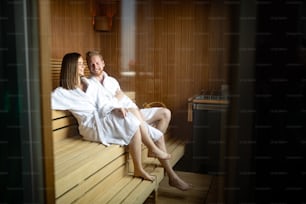 Gente hermosa en batas de baño usando sauna en balneario