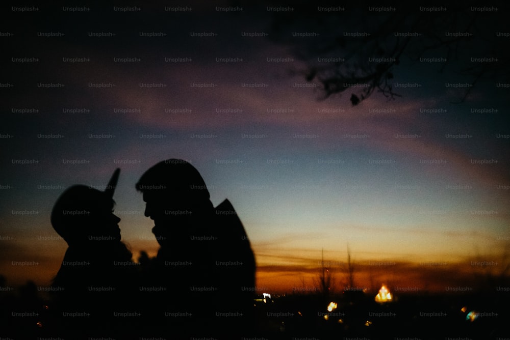 silhouette of happy couple looking at each other and touching with gentle on background of sunset sky and city lights