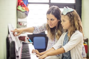 Miniature maestro. Child in music school with teacher.