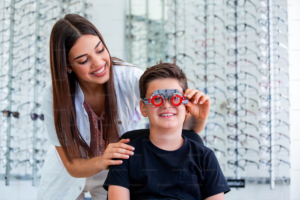 Attraente oftalmologo che esamina il ragazzo con il telaio di prova dell'optometrista. Paziente bambino per controllare la vista in clinica oftalmologica.