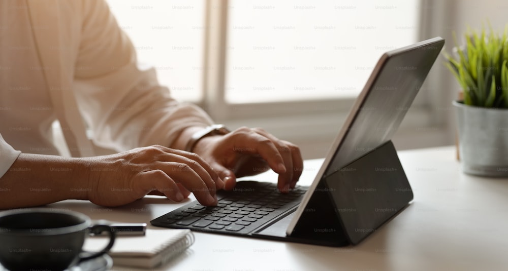 Vista lateral do jovem empresário profissional trabalhando em seu plano enquanto digita no laptop
