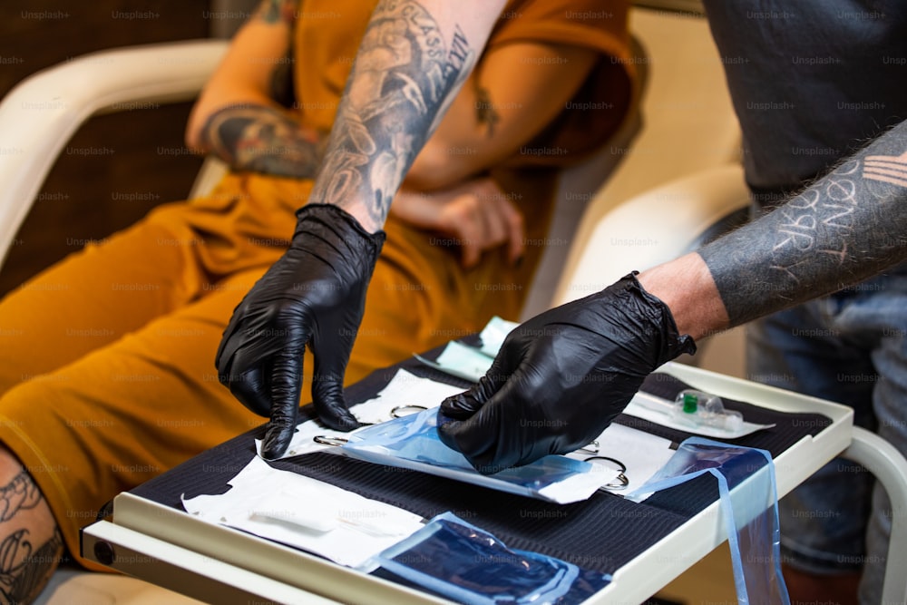 Close up of man opening steril equipment for piercing. Piercings getting ready for Procedure. Body piercing salon. Woman getting a piercing