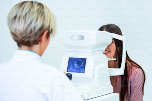 Female doctor ophthalmologist is checking the eye vision of attractive young woman in modern clinic. Doctor and patient in ophthalmology clinic