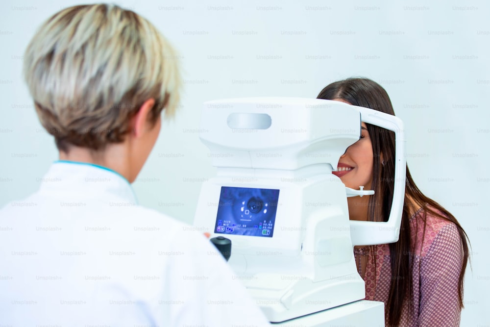 Oftalmologista médica está verificando a visão ocular de uma jovem atraente na clínica moderna. Médico e paciente em clínica oftalmológica