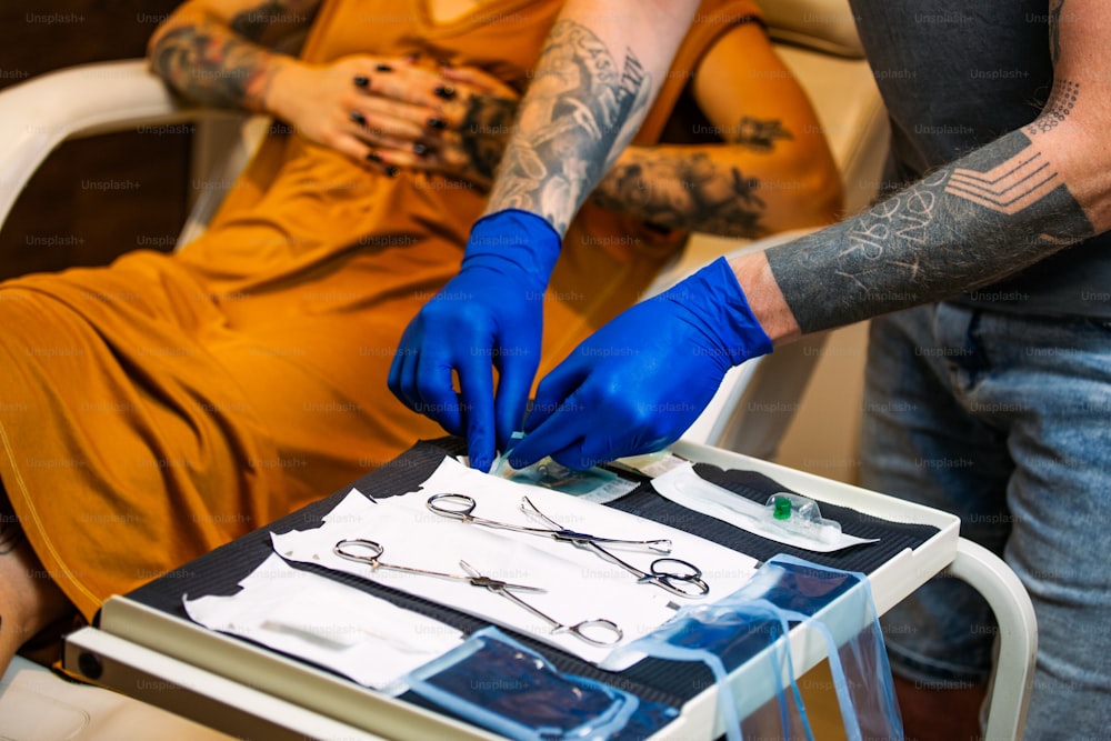 Close up of man opening steril equipment for piercing. Piercings getting ready for Procedure. Body piercing salon. Woman getting a piercing