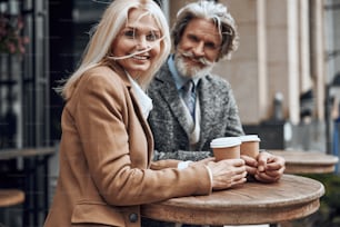 Fröhliche Frau, die sich umdreht und lächelt, während sie mit dem Mann am Cafétisch steht