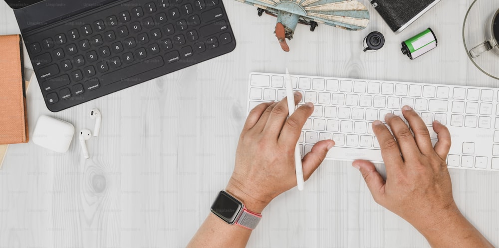 Tiro cenital de hombre escribiendo en el teclado en una oficina de estilo minimalista