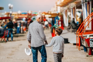 Grandfather and grandson having fun and spending good quality time together in amusement park.