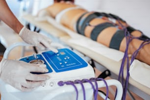 Tratamiento médico de salud y belleza de tecnología moderna con máquina de adelgazamiento EMS de electroestimulación.