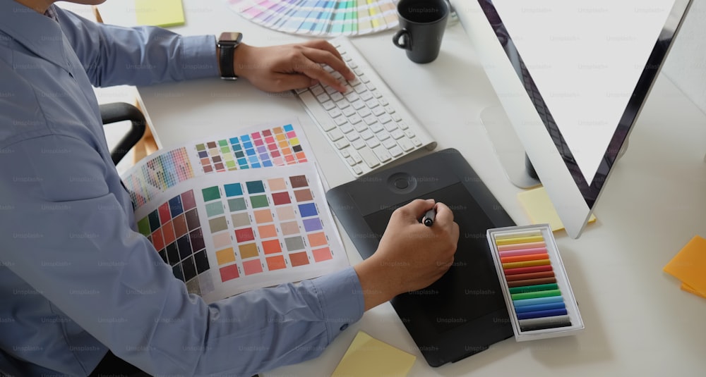 Diseñador gráfico que trabaja con tableta de dibujo y muestras de color
