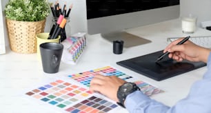 Graphic designer working with drawing tablet and colour swatches