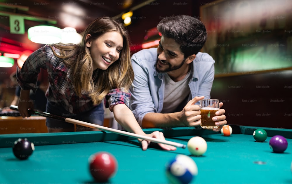 Couple drinking beer, having fun and playing snooker on date