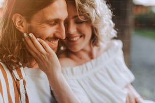 Close up portrait of happy young woman touching face of her boyfriend. They closing eyes and smiling