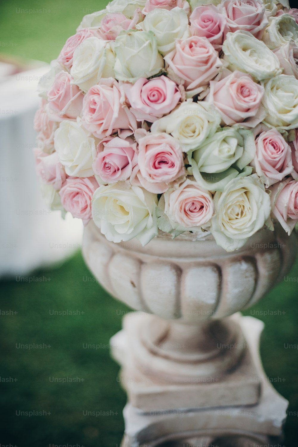 Elegant wedding bouquet on column, stylish decor of wedding aisle outdoors. Pink and white roses arrangement at wedding reception in botanical garden in Stresa