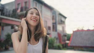 中国、北京のチャイナタウンで旅行中に、チャット、ソーシャルメディアのチェック、音楽の聴き方にスマートフォンを使用しているアジアのバックパッカーブロガーの女性。ライフスタイルバックパック観光旅行の休日のコンセプト。