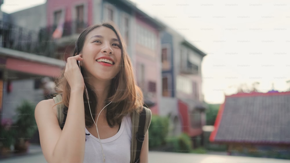 Mujer bloguera mochilera asiática que usa un teléfono inteligente para chatear, revisar las redes sociales y escuchar música mientras viaja en Chinatown en Beijing, China. Concepto de vacaciones de viaje turístico de mochila de estilo de vida.