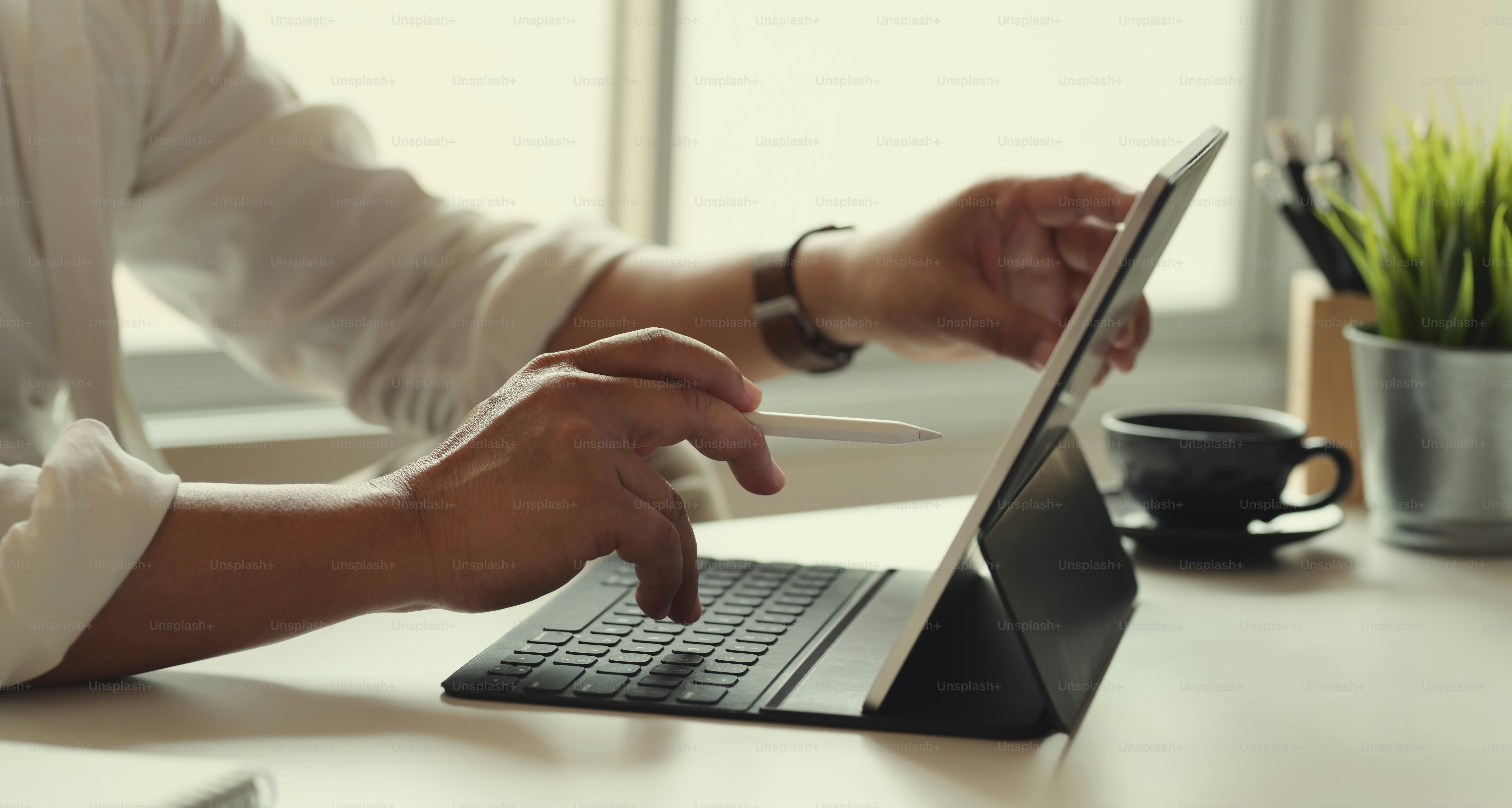 Close-up of businessman working on his project with stylus pen in workspace