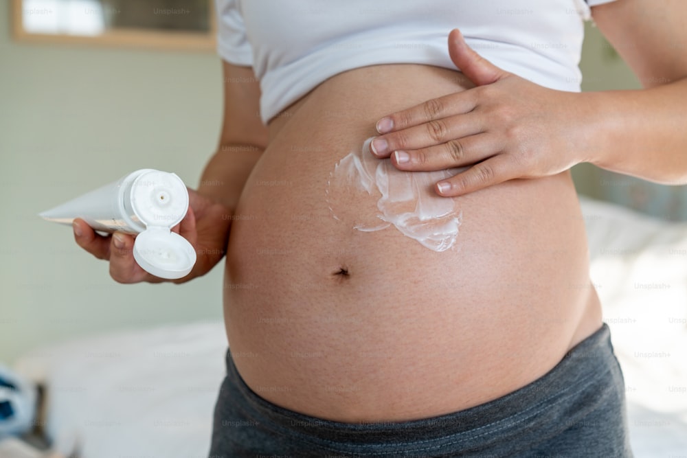 행복한 임산부는 튼살을 방지하기 위해 임신한 배에 스킨케어 크림 로션을 바릅니다. 건강한 피부 마사지 트리트먼트와 수분 관리 개념.