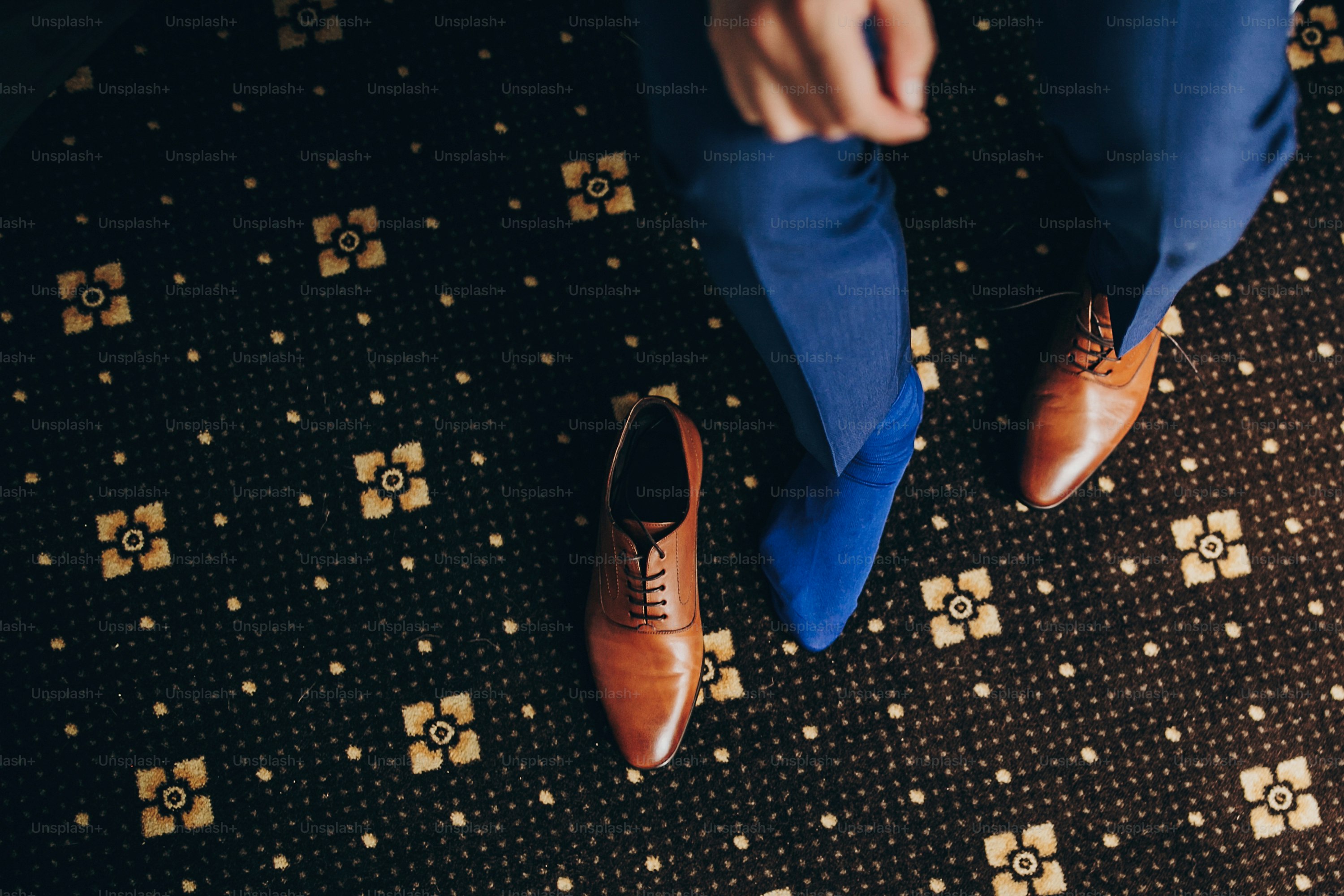 Stylish groom in blue suit putting on brown shoes near window in hotel  room, top view. Morning preparation before wedding ceremony. Man getting  ready before luxury event photo  Blue Image on
