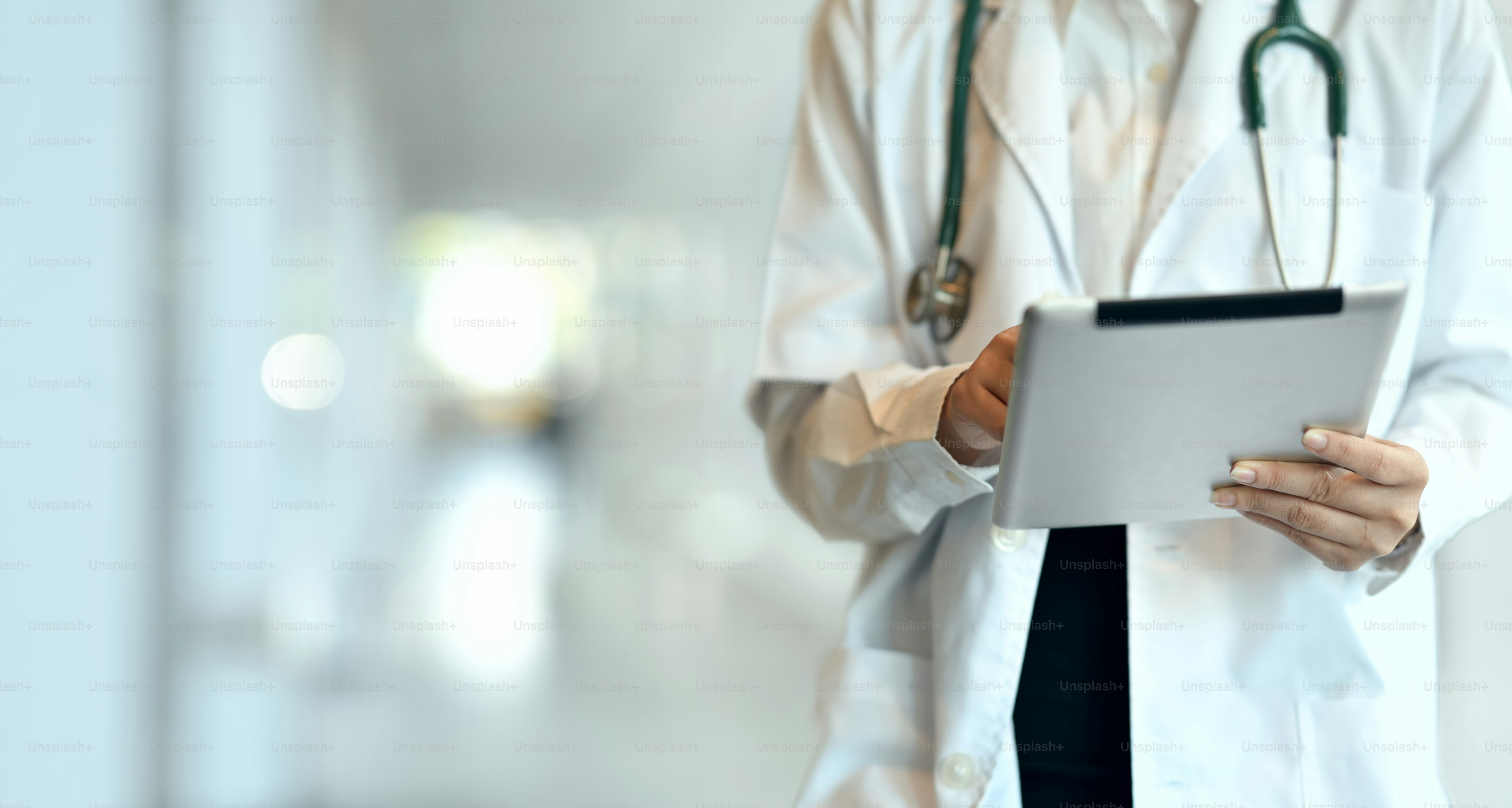 Primer plano del joven médico profesional que resume la historia clínica del paciente con la tableta en el hospital
