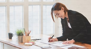 Leidenschaftliche junge Geschäftsfrau arbeitet mit Freude an ihrem Projekt in einem komfortablen Büro