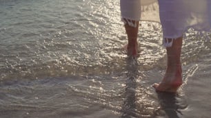 Young Asian woman walking on beach. Beautiful female happy relax walking on beach near sea when sunset in evening. Lifestyle women travel on beach concept.