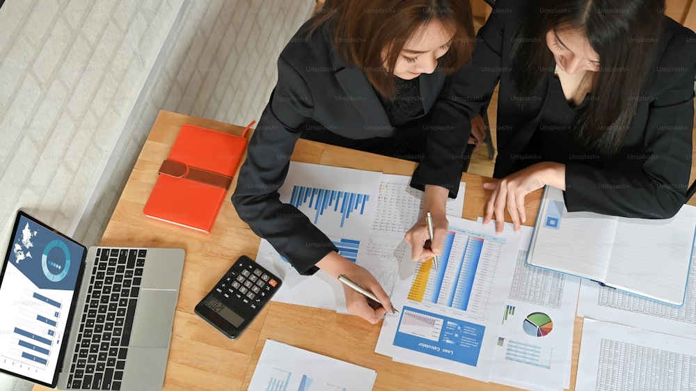 Top view business team discussing their plan meeting with charts and graphs on office desk, finance control concept.