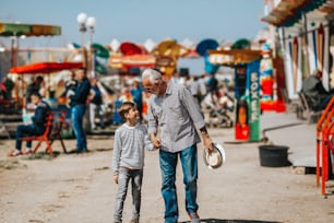 Grandfather and grandson having fun and spending good quality time together in amusement park.