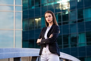 business woman with crossed arms. confident modern business woman standing near a large window in the office.