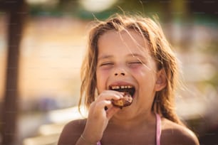 Time for break. Little girl eating desert on the beach.