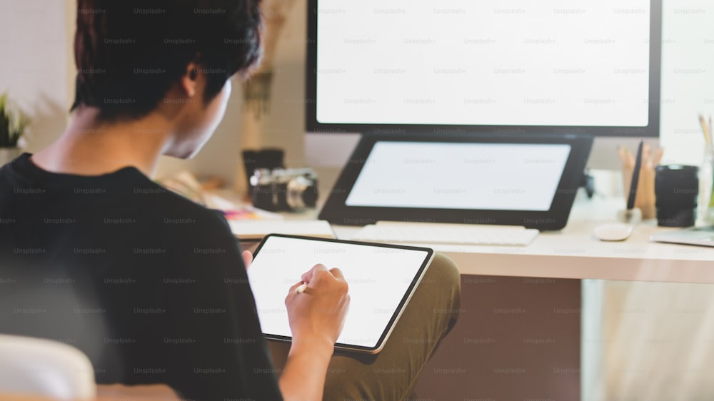 Young professional male photographer retouching his photos with digital tablet in comfortable workplace