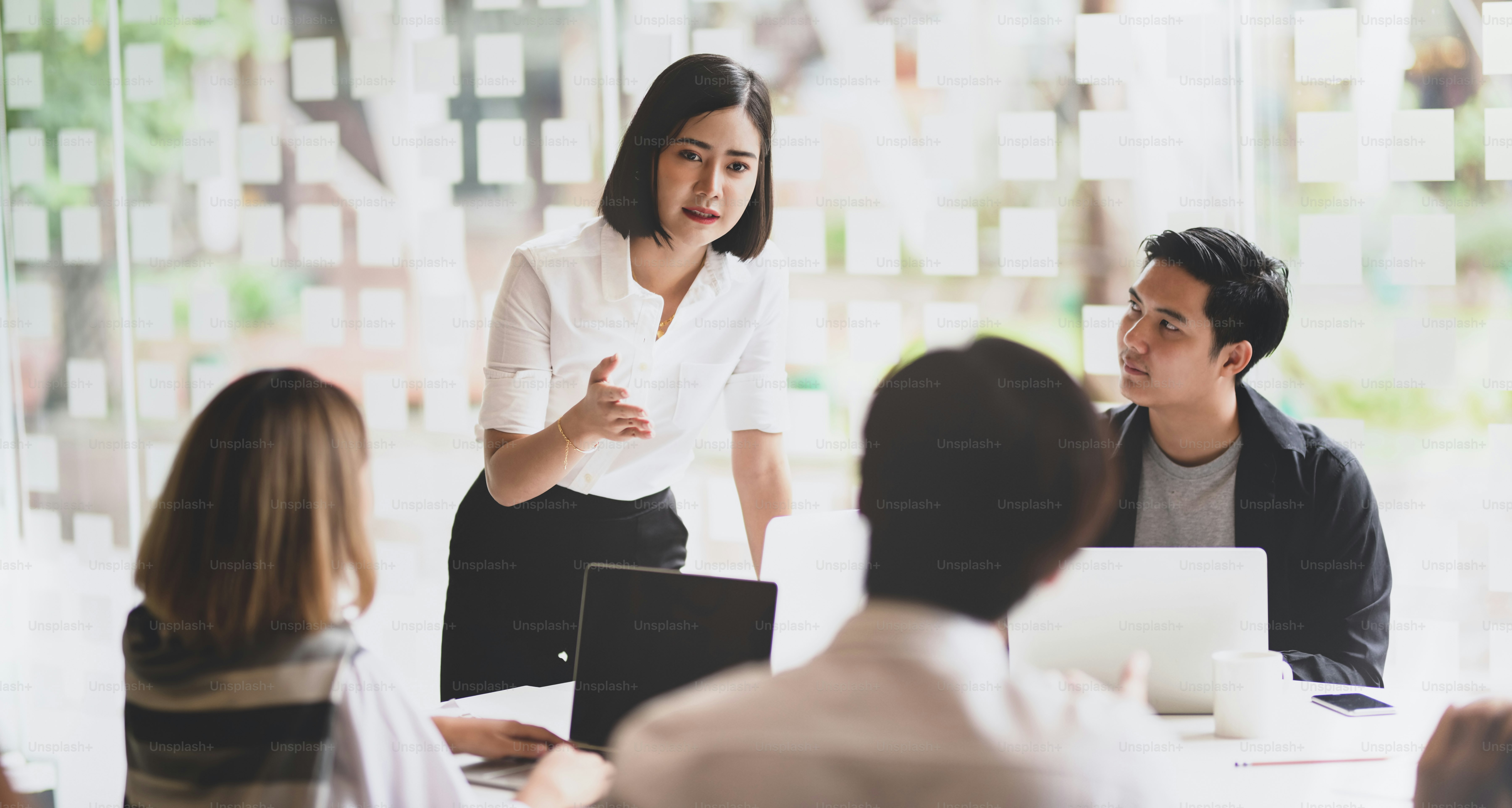 Young hardworking businesswoman explaining her strategy to her team members in meeting room with confident