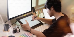Close-up view of motivated photographer drawing on tablet in his minimal workplace