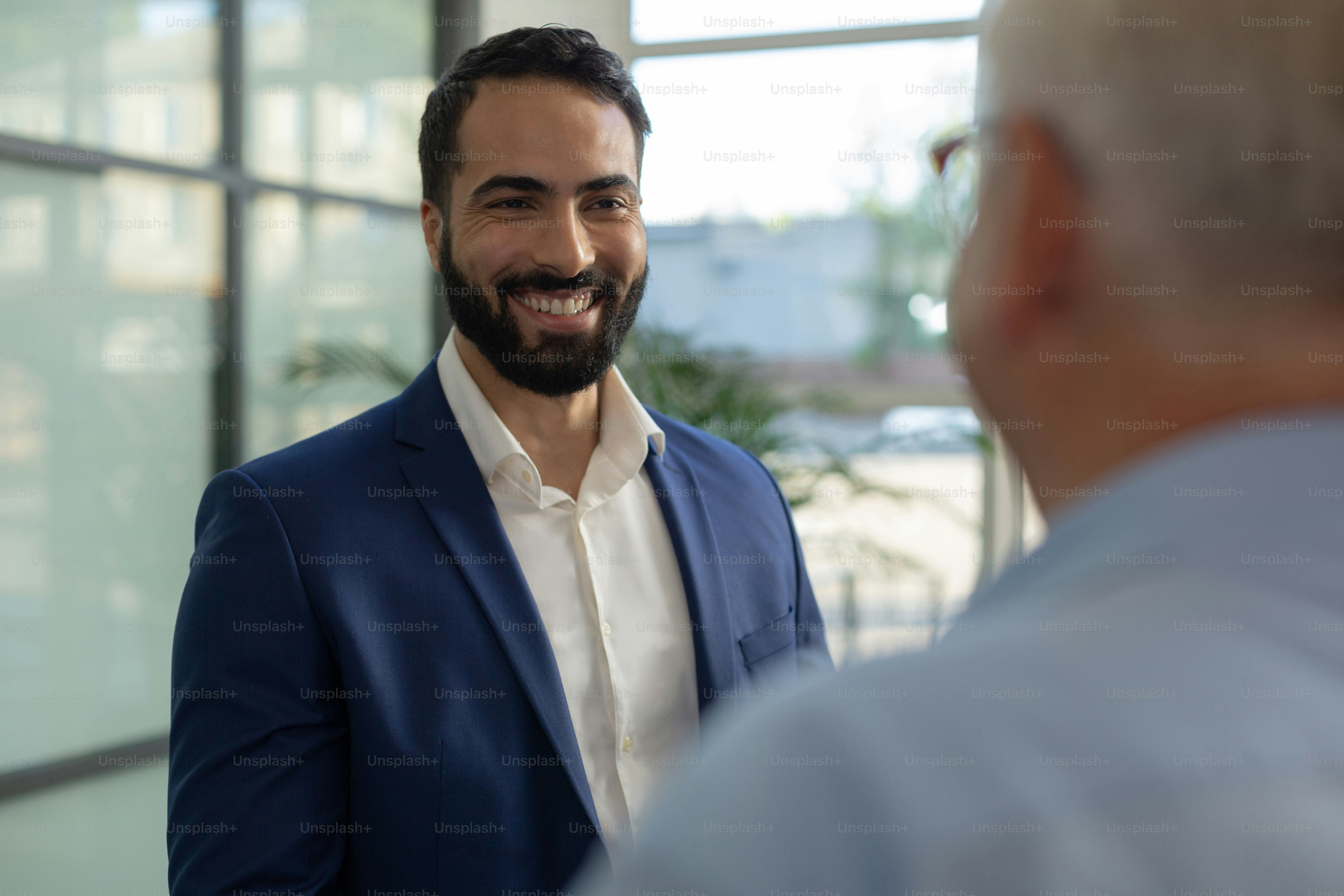 Welcome here. Cheerful bearded man keeping smile on his face while enjoying  friendly conversation photo – Meeting Image on Unsplash, image size:3000x2000