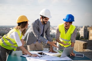 Team of architects and engineer in group on construciton site check documents