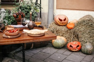 Halloween street decor. Jack o lantern pumpkins on hay in city street, holiday decor of cafe and tables. Autumn market in town. Space for text. Trick or treat. Happy halloween