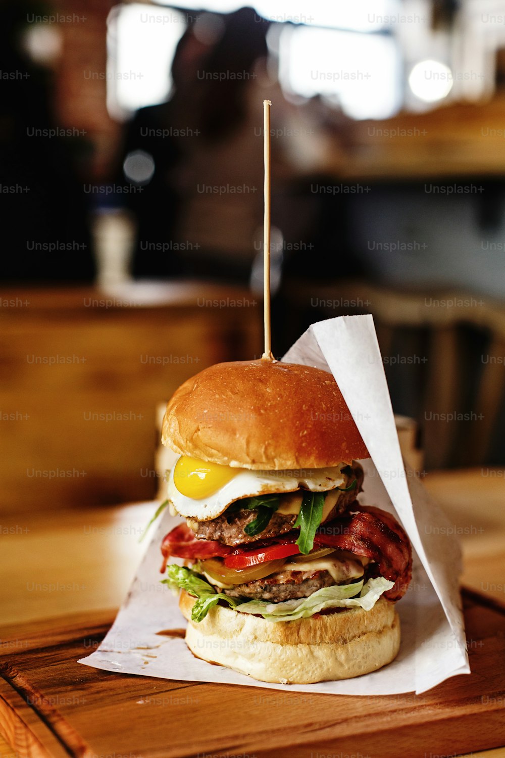 very big juicy burger with vegetables meat cutlet and egg on wooden background, space for text