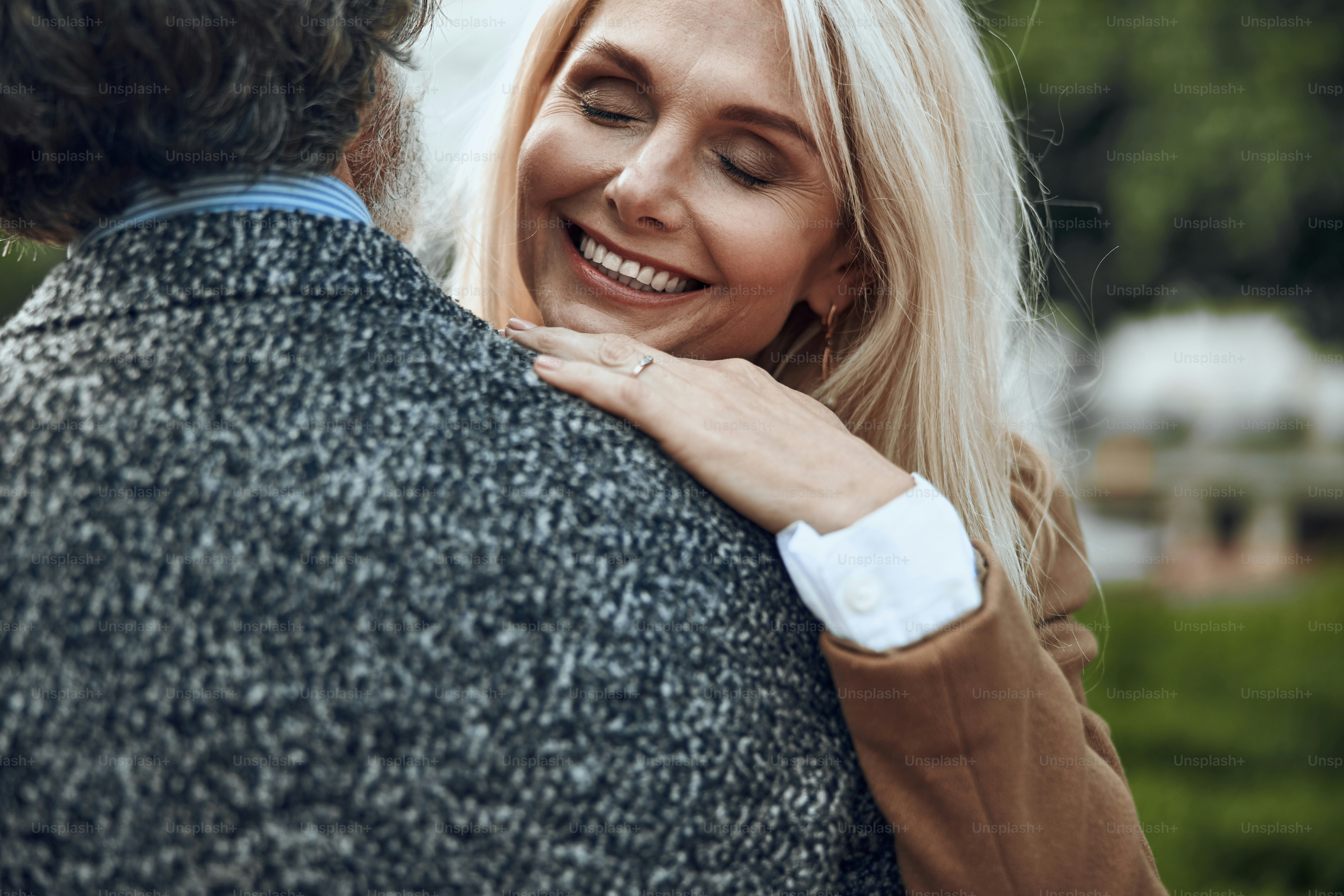 Cheerful mature woman laughing with closed eyes on the shoulder of man
