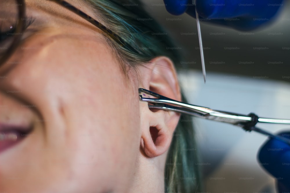 Ritratto di una donna che si fa forare l'orecchio. Uomo che mostra un processo di piercing all'orecchio. Pulire l'orecchio e renderlo sterile. Procedura di piercing all'orecchio