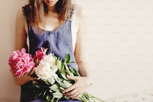 woman hipster in denim dress holding peony bouquet in the morning, sweet romantic moment , space for text